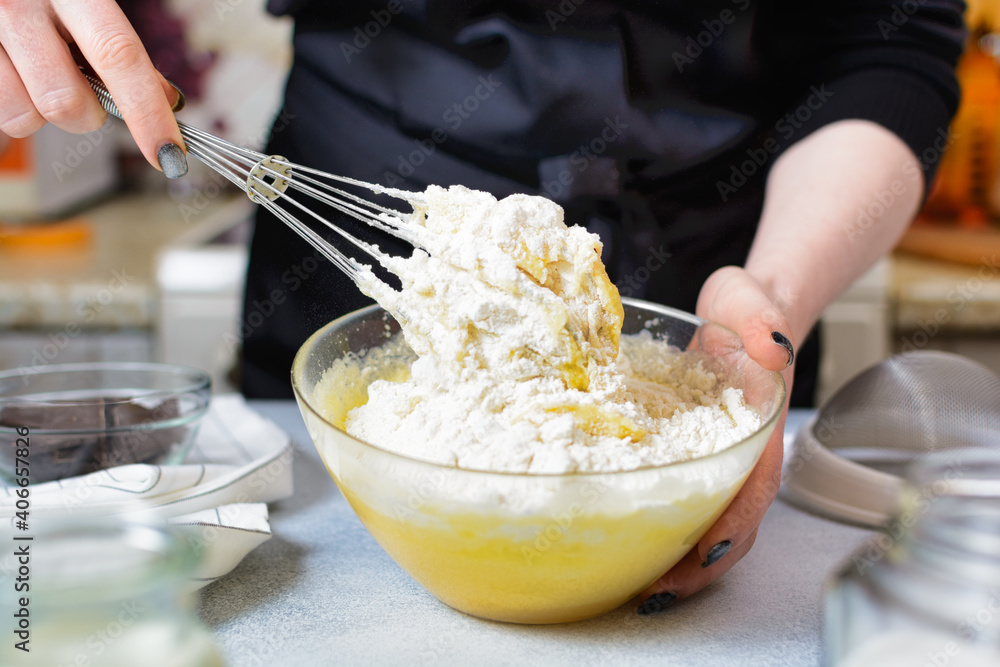 the chef prepares flour dough with a metal whisk in a glass bowl the chef prepares flour dough with a metal whisk in a glass bowl