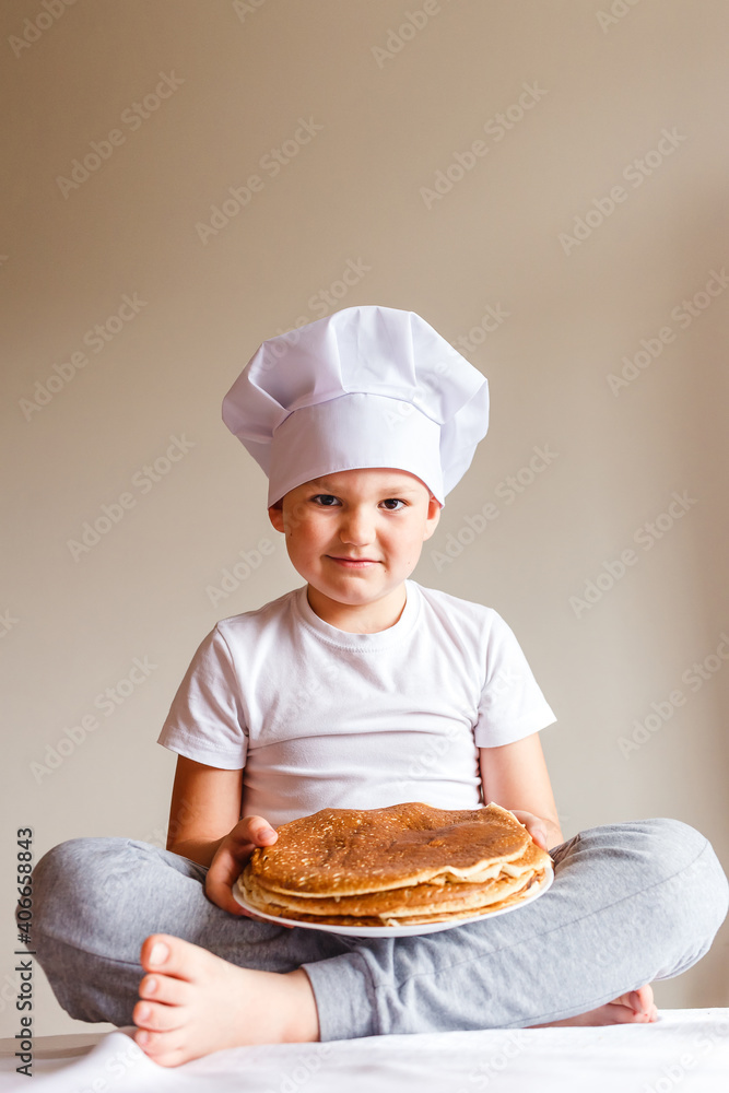 Photo shoot baby in white chef cap with pancakes on white background . Carnival Festival Photo shoot baby in white chef cap with pancakes on white background . Carnival Festival