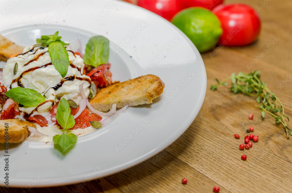 Soft cheese, baguette with tomatoes on a white plate. Close-up Soft cheese, baguette with tomatoes on a white plate. Close-up