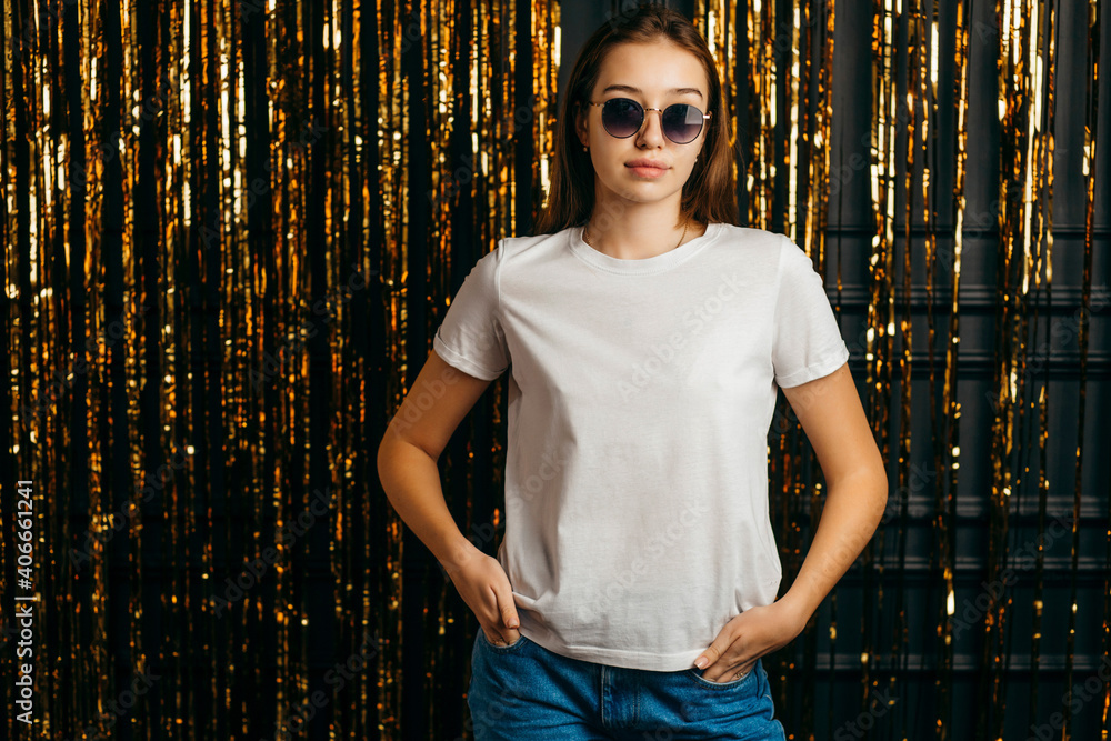 Fototapeta premium Stylish girl wearing white t-shirt and sunglasses posing in studio