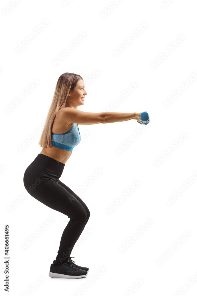 Full length profile shot of a young woman in sportswear exercising with small blue weigths Full length profile shot of a young woman in sportswear exercising with small blue weigths