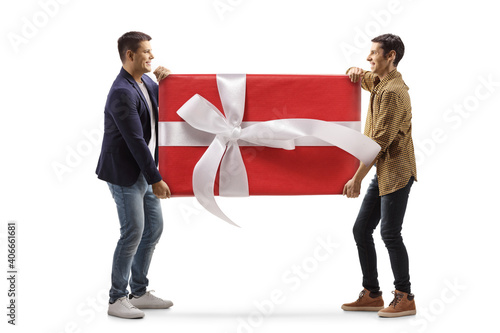 Full length profile shot of two young men carrying a big wrapped present photo