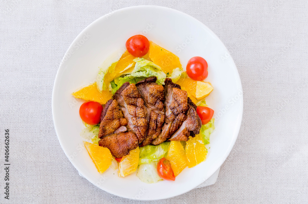 Roasted duck with fresh tomatoes, orange, herbs on a white plate. View from above Roasted duck with fresh tomatoes, orange, herbs on a white plate. View from above