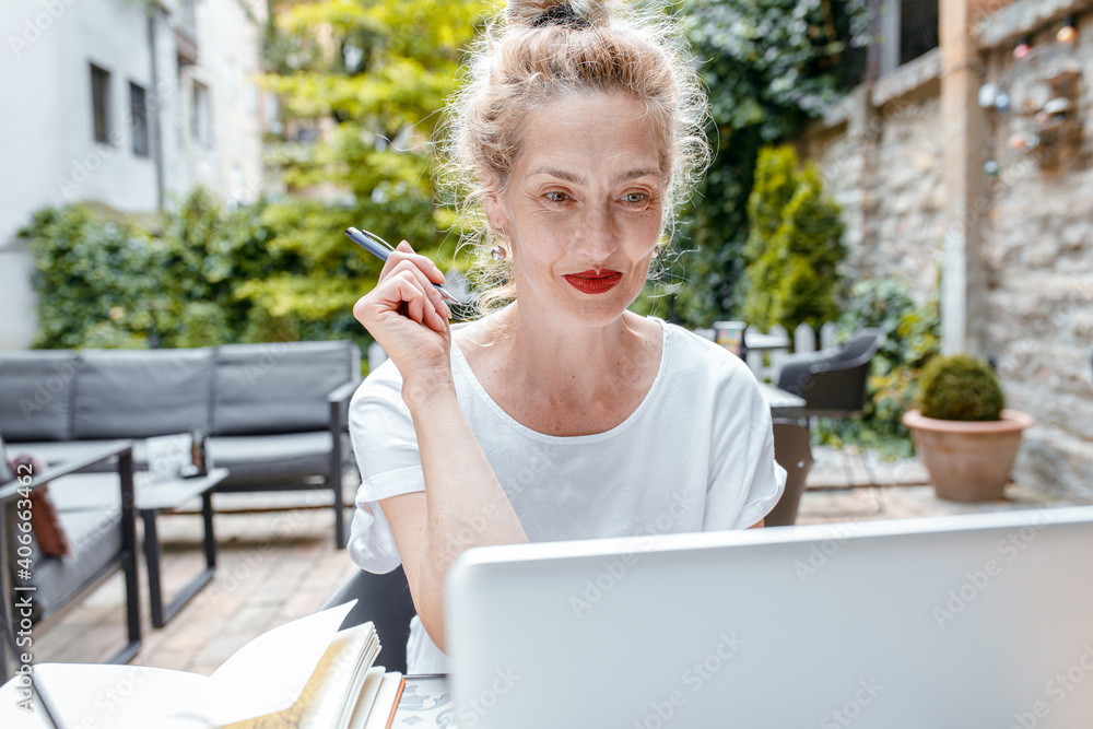 Fototapeta premium Smiling senior woman sitting in coffee shop using laptop.