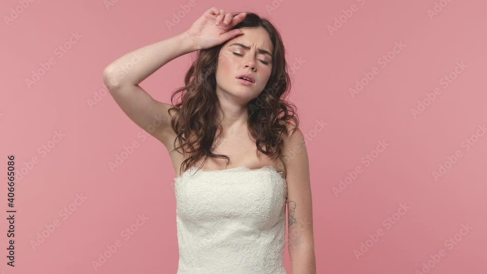 Exhausted tired upset bride young woman 20s in beautiful white wedding dress isolated on pink background studio. Wedding concept. Put hand on head yawn cover mouth did not get enough sleep last night Exhausted tired upset bride young woman 20s in beautiful white wedding dress isolated on pink background studio. Wedding concept. Put hand on head yawn cover mouth did not get enough sleep last night