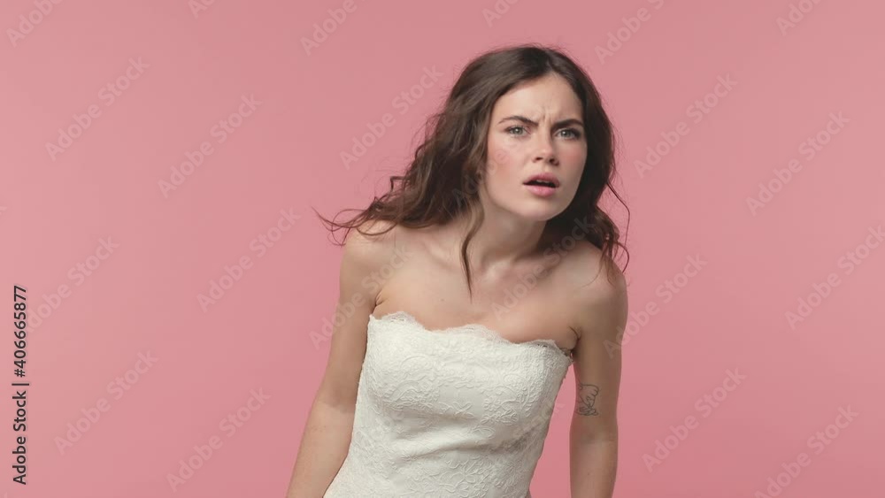 Surprised bride young brunette woman 20s years old in beautiful white wedding dress posing isolated on pink pastel background studio. Wedding concept. Waving and greeting with hand as notices someone Surprised bride young brunette woman 20s years old in beautiful white wedding dress posing isolated on pink pastel background studio. Wedding concept. Waving and greeting with hand as notices someone
