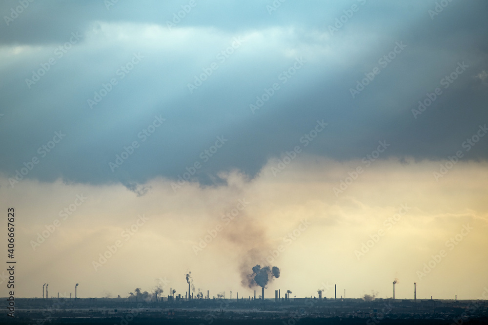 silhouette of oil refinery with heavy clouds above at sunset