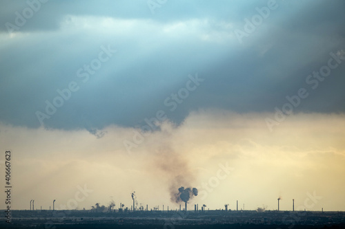 silhouette of oil refinery with heavy clouds above at sunset