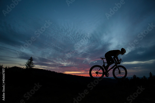 The silhouette of the cyclist on bike at sunset.A man ride on bike on the mountains. Sport and active life concept sunset time. A man riding a bicycle in a nature.
