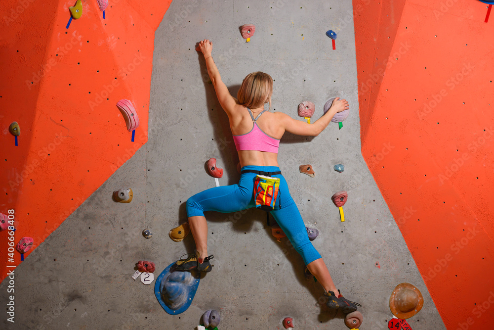 Naklejka premium Woman Climber Practicing Rock-climbing in the Bouldering Gym. Extreme Sport and Indoor Climbing Concept