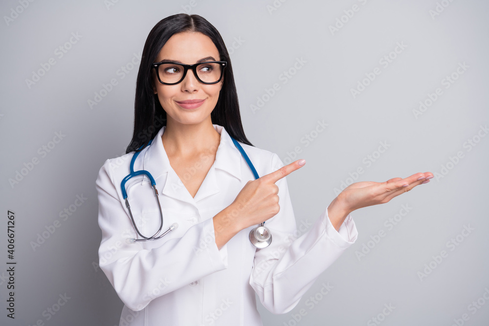 Photo of adorable confident woman therapist dressed white uniform pointing holding arm empty space isolated grey color background Photo of adorable confident woman therapist dressed white uniform pointing holding arm empty space isolated grey color background