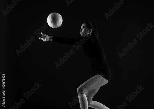 Volleyball girl hold and kick ball on dark background. Player doing sport workout online. Sport and recreation concept. Black and white color filter