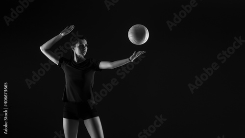 Volleyball girl hold and kick ball on dark background. Player doing sport workout online. Sport and recreation concept. Black and white color filter