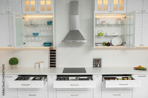 Open cabinets with different clean tableware and utensils in kitchen