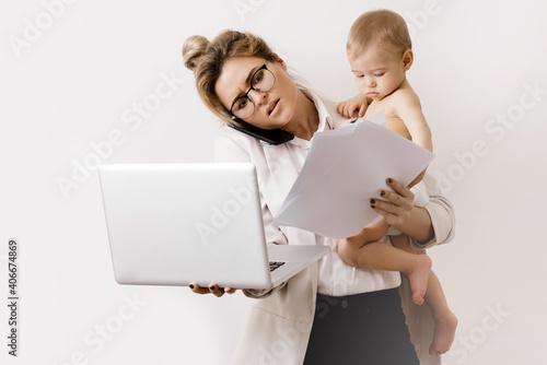 Young and busy businesswoman is working and holding her little baby