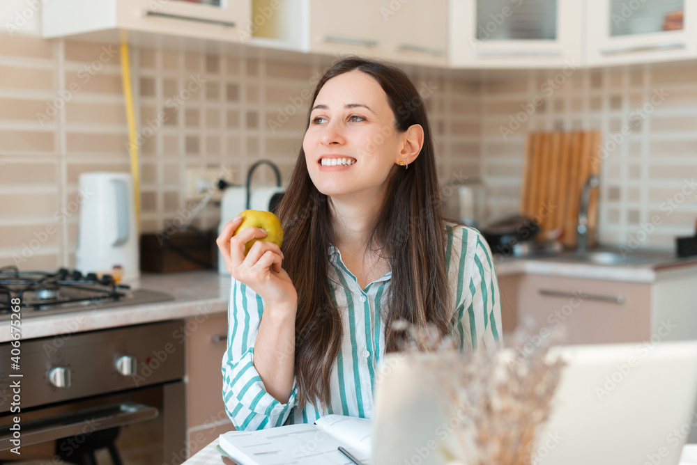Photo of young woman eating an apple in pause of work from home.
