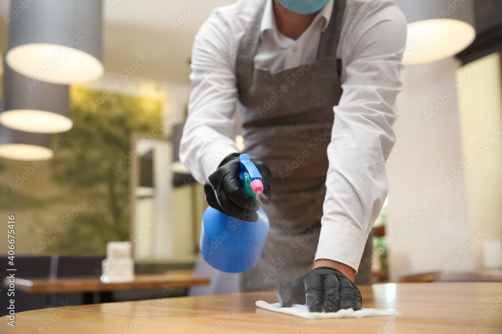 Waiter cleaning table with rag and detergent in restaurant, closeup. Surface treatment during coronavirus pandemic - obrazy, fototapety, plakaty 