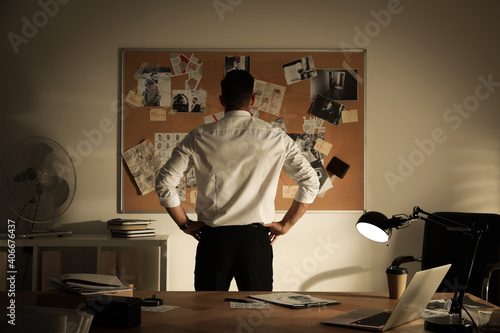 Detective looking at evidence board in office photo