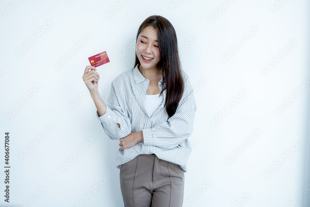 Portrait of a lovely young Asian beautiful woman with long hair holding a red credit card, her eyes sparklingly at the camera. Ready to pay shopping according to discounted products Portrait of a lovely young Asian beautiful woman with long hair holding a red credit card, her eyes sparklingly at the camera. Ready to pay shopping according to discounted products