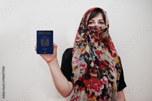 Young arabian muslim woman in hijab clothes hold United Arab Emirates passport on white wall background, studio portrait. photo
