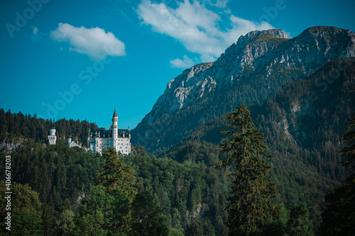 German Castle in the forest and mountains with blue sky and clouds