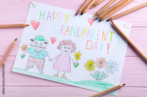 Beautiful drawing with phrase Happy Grandparents Day on pink wooden table, flat lay