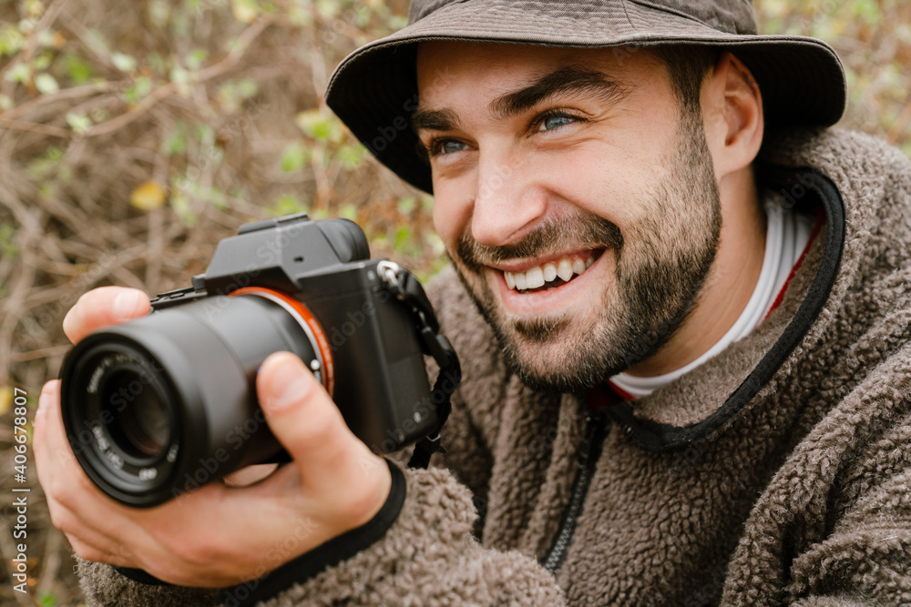 Obraz premium Happy handsome photographer smiling while taking photo on digital camera