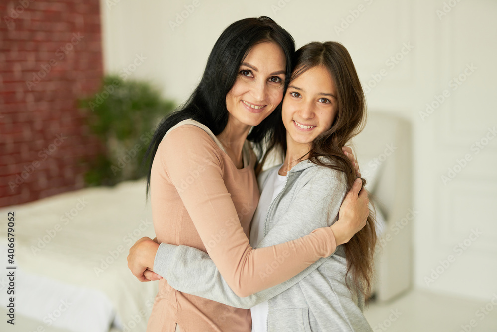 Forever best friend. Happy latin mother and daughter hugging each other, smiling at camera, looking affectionate while posing together indoors Forever best friend. Happy latin mother and daughter hugging each other, smiling at camera, looking affectionate while posing together indoors