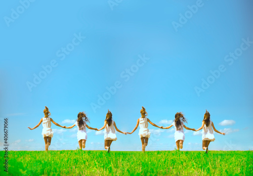 six running girls  at green grass at background of blue sky with clouds. 6 young adult woman walk on summer field. Empty space for inscription. Back view. No faces. Girlfriend concept. photo