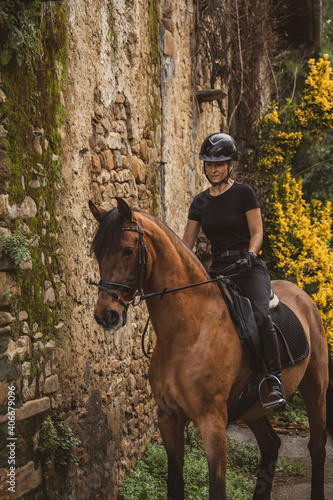 woman riding her brown horse with black mane dressed in black with a helmet