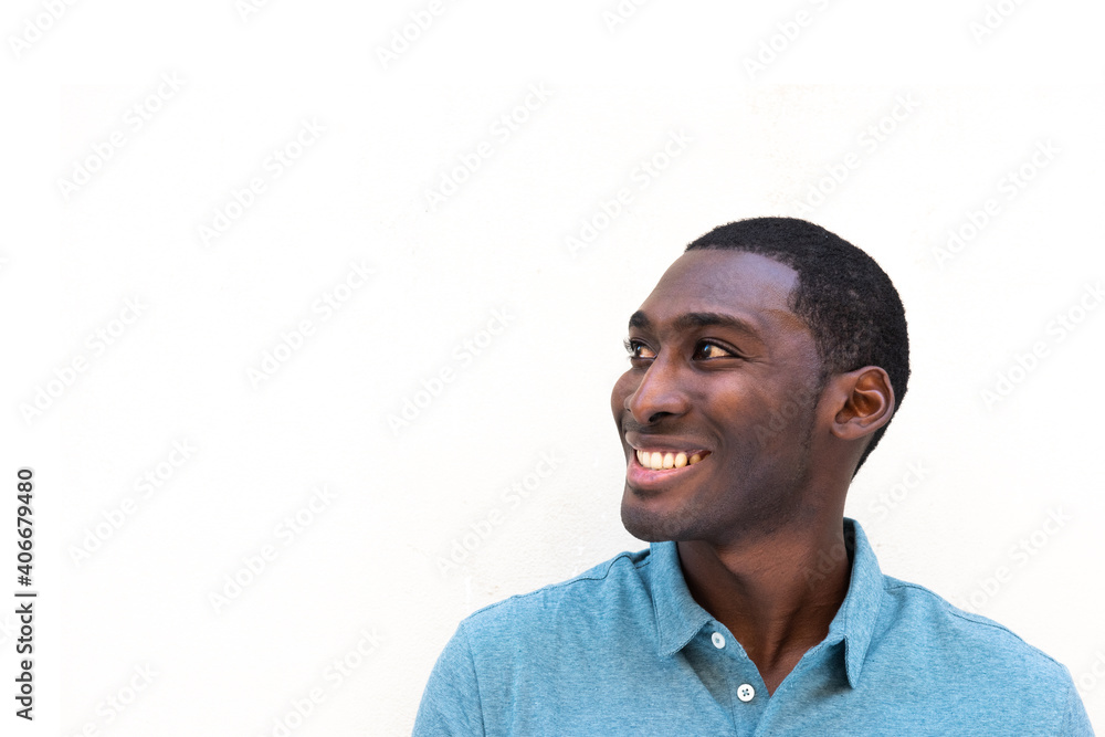 Close up smiling young black man by isolated white background looking away Close up smiling young black man by isolated white background looking away