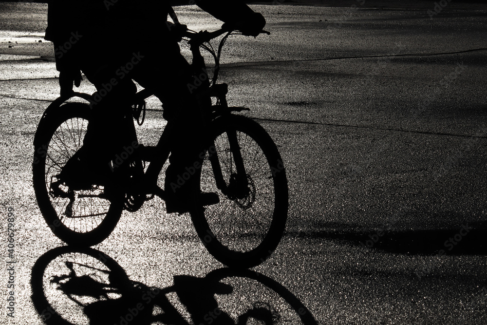 Obraz premium Black silhouette of a cyclist on the wet road. Person riding a bicycle, cycling concept, dramatic atmosphere