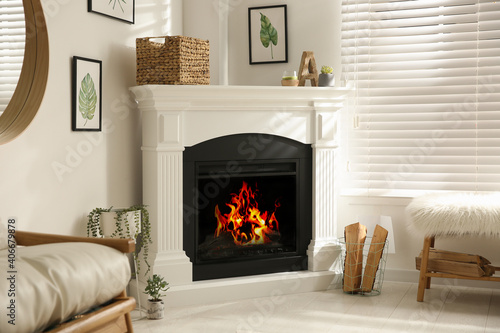 Fototapeta Bright living room interior with artificial fireplace and firewood in basket