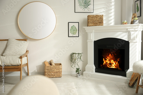 Foto Bright living room interior with artificial fireplace and firewood in basket