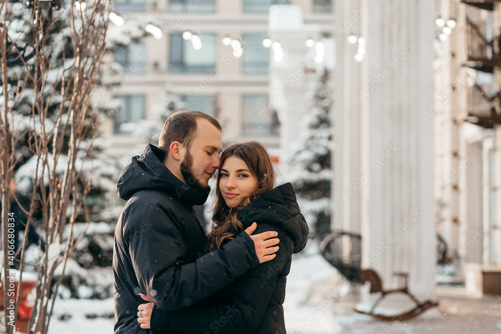 A loving couple in a gentle embrace against the background of a snowy city