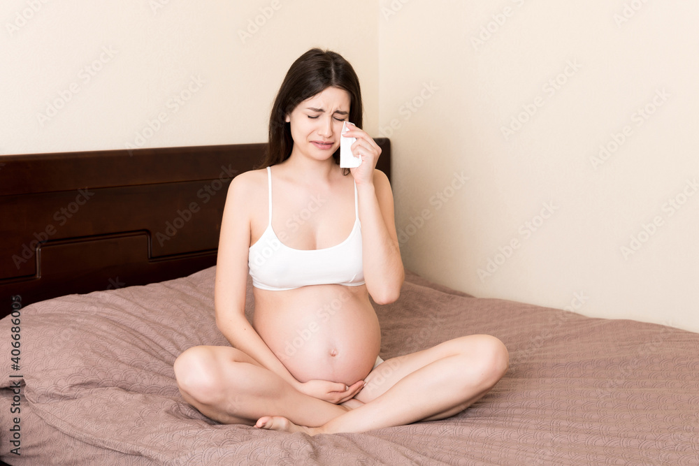 Attractive woman feeling sad and crying during her pregnancy Attractive woman feeling sad and crying during her pregnancy