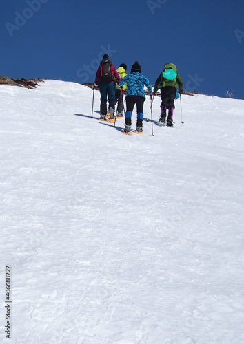 白い雪の平原をスノーシューで登る人たち