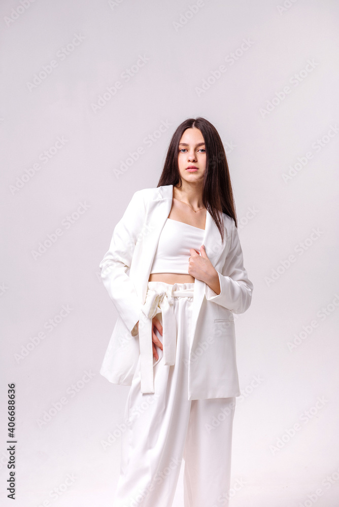 Fashion portrait of a beautiful brunette in white eco clothes on a white background Fashion portrait of a beautiful brunette in white eco clothes on a white background