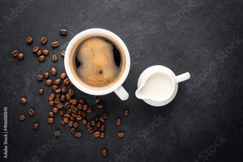 Tableau sur toile Cup of black coffee and coffee creamer in a jug on black concrete background, to