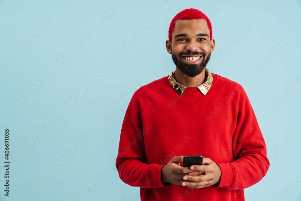 Happy african american guy smiling and using mobile phone Happy african american guy smiling and using mobile phone