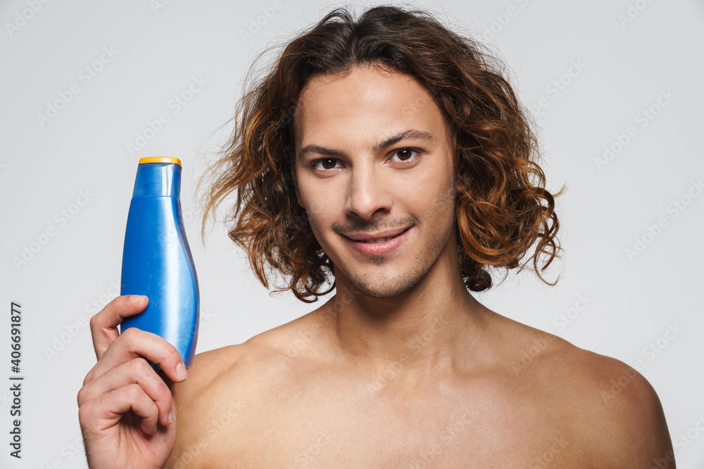 Happy shirtless guy smiling while posing with shampoo Happy shirtless guy smiling while posing with shampoo