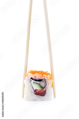 One sushi roll in chopsticks isolated on white background. Classic roll with salmon, cucumber and cheese. Traditional Japanese cuisine. Close up.