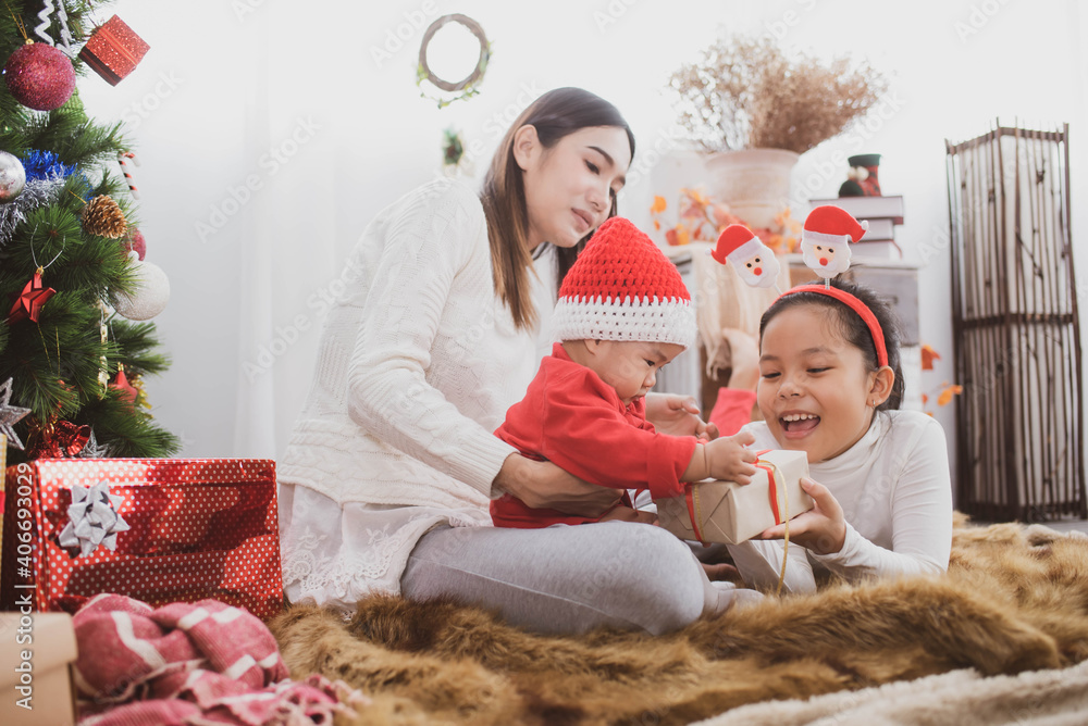 parent and two little children having fun and playing together near christmas tree indoors. merry christmas and happy holidays. cheerful mom and her cute daughters girls exchanging gifts. parent and two little children having fun and playing together near christmas tree indoors. merry christmas and happy holidays. cheerful mom and her cute daughters girls exchanging gifts.