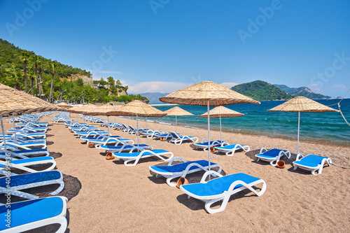 Fototapeta Naklejka Na Ścianę i Meble -  beach on the sea in cloudless weather. Sunset on a sandy beach with umbrellas and sun loungers