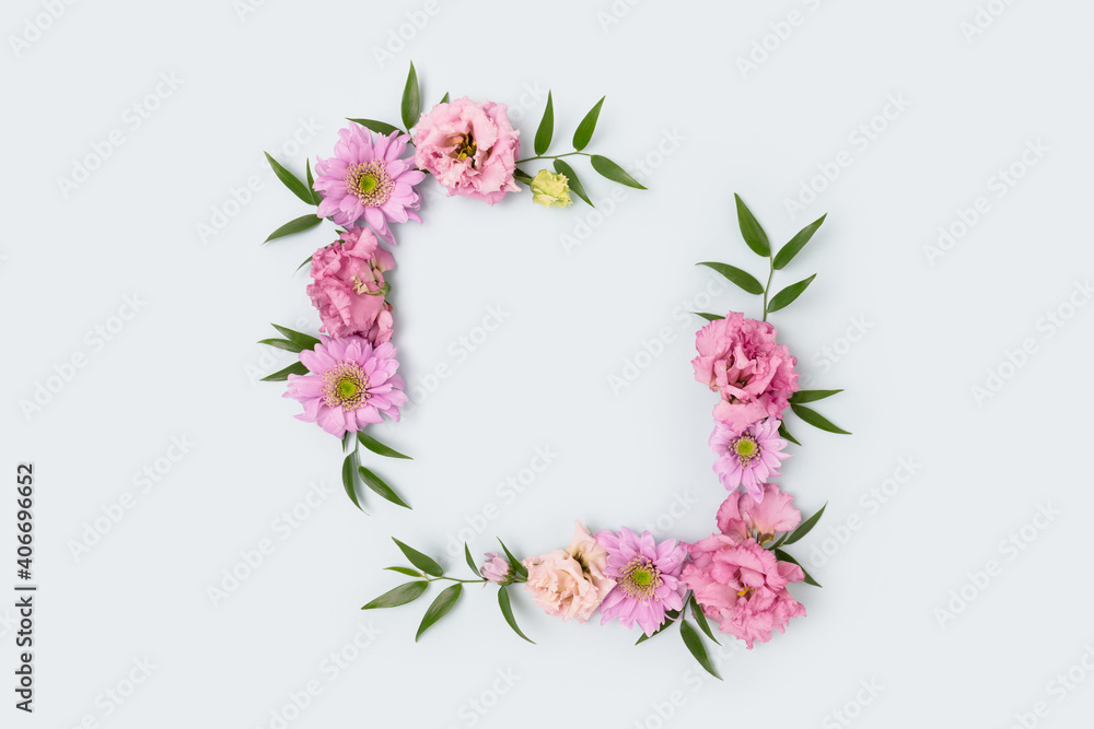 Empty flower frame made of pink eustoma on blue background. Greeting card template with copyspace. Spring concept.