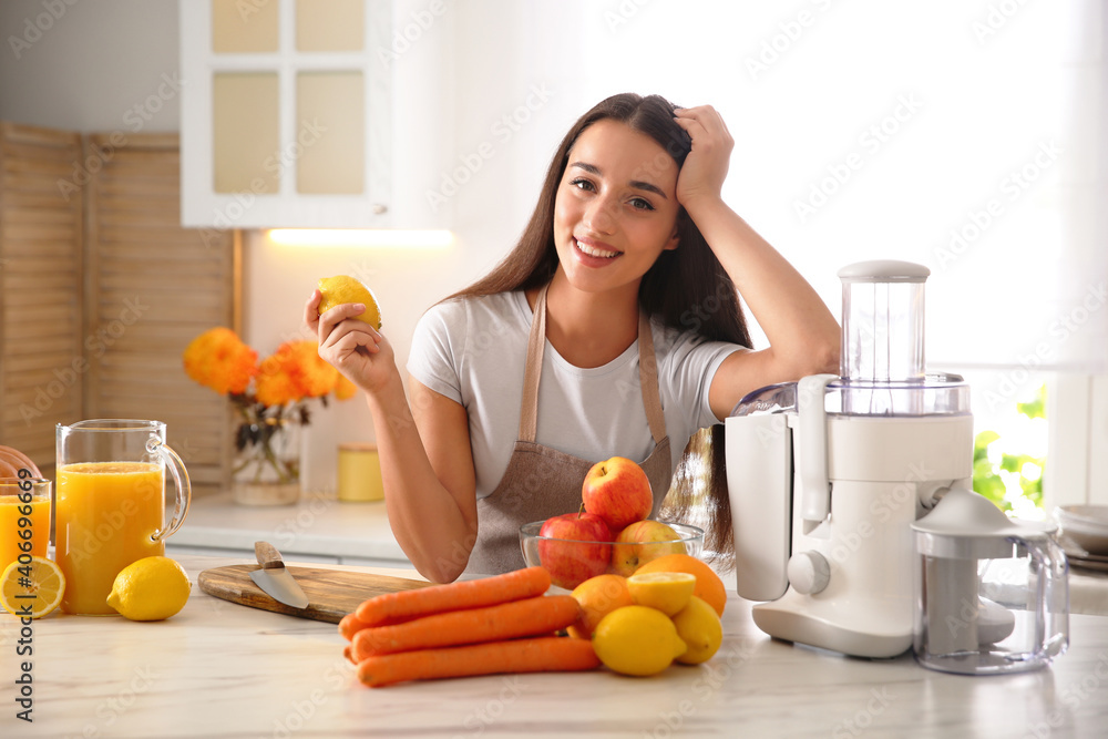 Young woman making tasty fresh juice at table in kitchen Young woman making tasty fresh juice at table in kitchen