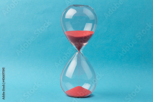 Crystal hourglass on blue background as a concept of passing time for business term, urgency and outcome of time.