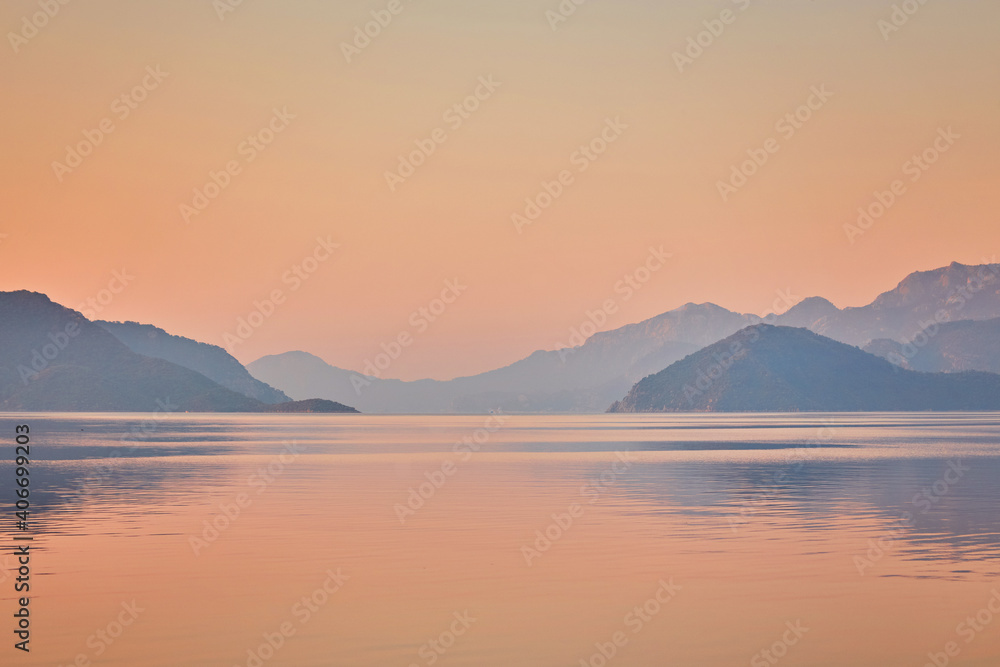 Mountain reflected sunrise in calm sea