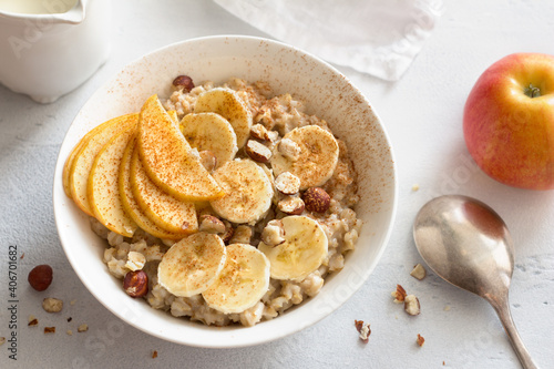 Delicious healthy breakfast. Oatmeal with banana, apple, nuts and cinnamon on a light gray background, top view	
