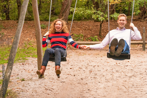 Young couple swings in the playground. the man and wife are in l